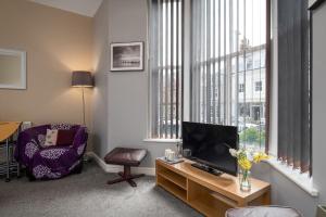 a living room with a tv and a chair at 2 bedroom Llandudno holiday apartment in Llandudno