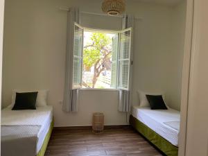 - 2 lits dans une chambre avec fenêtre dans l'établissement Via De Bosset City Cottage, à Argostóli