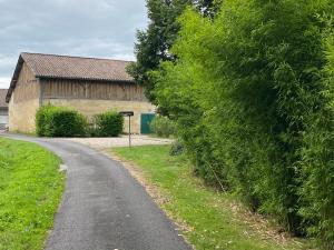 a road next to a barn with a large hedge at 16 CHEMIN DE BOISBELET in Coutras