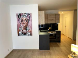une cuisine avec une peinture d'une femme sur le mur dans l'établissement Très bel appartement T2 de standing entièrement meublé à 5 min à pied du centre., à Divonne-les-Bains