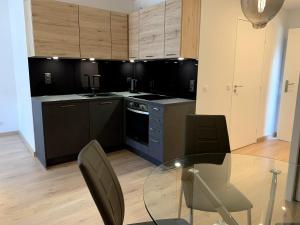 une grande cuisine avec une table et des chaises en verre dans l'établissement Très bel appartement T2 de standing entièrement meublé à 5 min à pied du centre., à Divonne-les-Bains