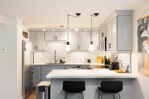 a kitchen with white cabinets and black stools at Madison Park Seattle with Outdoor Private Garden and Grill 1BR 1BA in Seattle