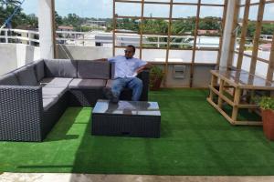 un hombre sentado en un sofá en un balcón en DB Tower Vacation Rental en Ciudad de Belice