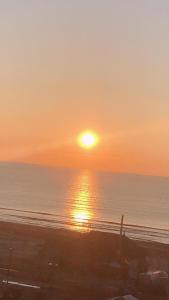 un tramonto sulla spiaggia con il sole che tramonta sull'oceano di Astoria Lux Seashore 23 a Năvodari