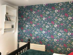 
a room with a bed, a wall and a painting on the wall at 1 Phoenix Cottages, 403 High Street, Cheltenham in Cheltenham

