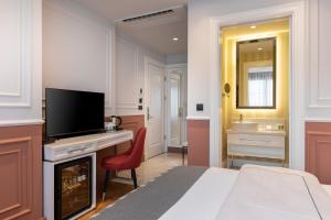 a bedroom with a bed and a desk with a television at Motif Hotel Çeşme in Çeşme