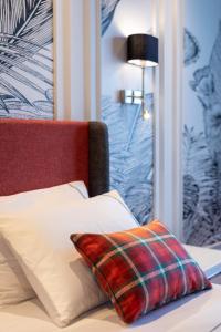 a bed with a plaid pillow on top of it at Motif Hotel Çeşme in Çeşme