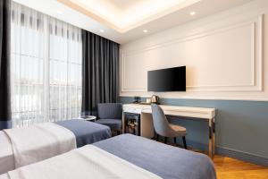 a hotel room with two beds and a desk at Motif Hotel Çeşme in Çeşme