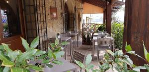 un restaurante con mesas blancas, sillas y plantas en Locanda Le Volte en Casale Marittimo