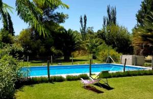 a swimming pool with a chair in the grass at Casa Quinta Rodeada de Bodegas Piscina BBQ Mendoza in Maipú