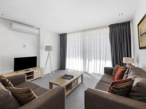 a living room with two couches and a flat screen tv at Resort Apartment 109 in Torquay