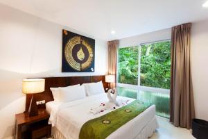 um quarto com uma cama grande e uma janela em The Park Surin Serviced Apartments em Praia de Surin