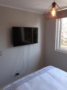 a bedroom with a bed and a tv on the wall at Departamento en Pucón in Pucón