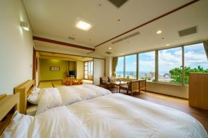 a bedroom with two beds and a large window at Hotel Beppu Pastoral in Beppu