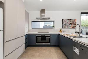 uma cozinha com armários brancos e azuis e um lavatório em Just built luxury Townhouse em Torquay