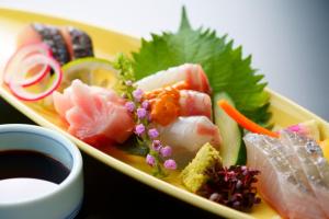 a yellow plate of food with sushi and vegetables at Hotel Beppu Pastoral in Beppu