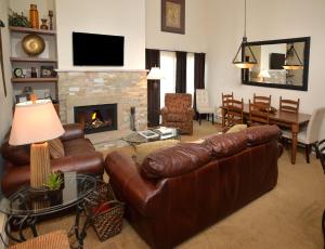 a living room with a leather couch and a fireplace at Lionshead Arcade #303 Condo in Vail