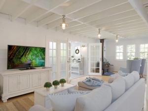un soggiorno con mobili bianchi e TV a schermo piatto di The Cottage a Kianga