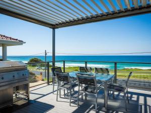 um pátio com uma mesa e cadeiras e o oceano em 81 Dalmeny Drive Beach House em Kianga