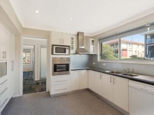 a kitchen with white cabinets and a large window at 81 Dalmeny Drive Beach House in Kianga