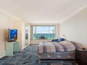 a bedroom with a bed and a flat screen tv at 81 Dalmeny Drive Beach House in Kianga