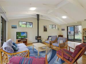 - un salon avec un canapé, des chaises et une télévision dans l'établissement 37 Coastal Court Bush Retreat By the Sea, à Dalmeny