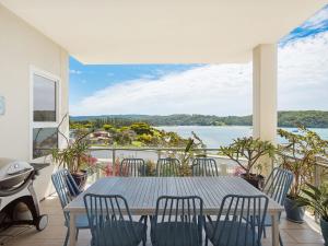 una mesa y sillas en un balcón con vistas al agua en Wharf Apartment Unit 5 en Narooma