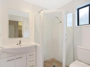 a white bathroom with a sink and a shower at 37 Coastal Court Bush Retreat By the Sea in Dalmeny +13 photos