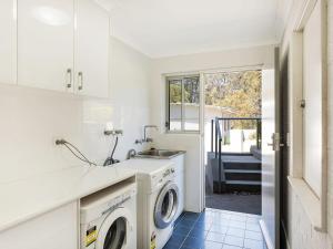 a kitchen with a sink and a washing machine at Bayview Ringlands in Narooma