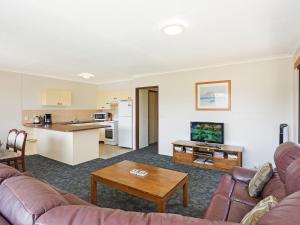a living room with a couch and a table at Unit 1, 2b Harrington Road in Narooma +8 photos