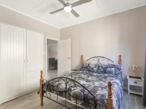 - une chambre avec un lit et un ventilateur de plafond dans l'établissement The Inlet Cottage, à Narooma