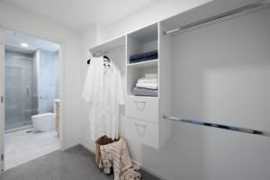 ein Badezimmer mit weißen Wänden und einer Schiebetür in der Unterkunft Sunrise Garden Serviced Apartments Albany in Auckland