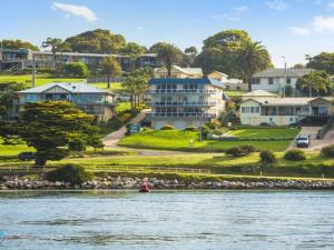 a person in a boat on the water in front of houses at Sapphire Waters Unit 3 in Narooma