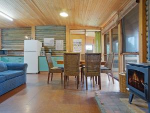 ein Wohnzimmer mit einem Tisch und Stühlen sowie einem Kühlschrank in der Unterkunft 98 Ocean Parade Rustic Log Cabin in Dalmeny