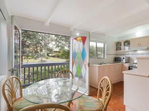 a kitchen with a glass table and chairs and a balcony at Pet friendly Beach House at Kianga in Kianga