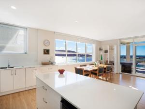a kitchen with white cabinets and a dining room with a table at Wharf Apartment Unit 7 in Narooma