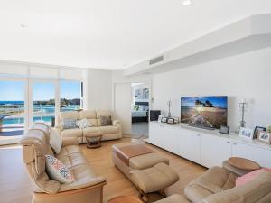 Il comprend un salon avec des canapés et une télévision à écran plat. dans l'établissement Wharf Apartment Unit 7, à Narooma