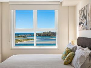 a bedroom with a window with a view of the ocean at Wharf Apartment Unit 7 in Narooma