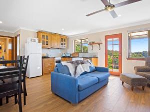 a living room with a blue couch and a kitchen at Braeside Cabin Four Ziera in Central Tilba