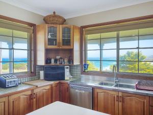 a kitchen with wooden cabinets and a view of the ocean at 120 Ocean Parade Dalmeny in Dalmeny