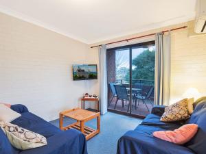 a living room with a blue couch and a table at Apollo Unit 23 First Floor in Narooma