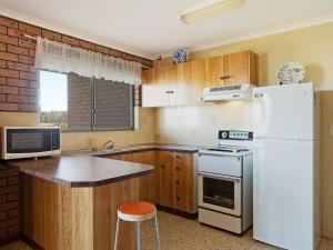 a kitchen with wooden cabinets and a white refrigerator at Grandview Apartment Ocean Views in Kianga