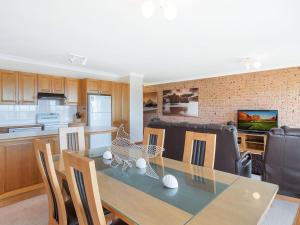 
a kitchen with a table, chairs and a microwave at Grand Pacific 2 Unit 2 in Narooma
