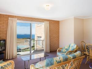 
a room with a couch, chair, table and a window at Countess Court Unit - Great Ocean Views in Narooma
