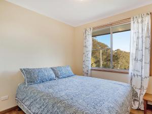 
a bed sitting in a bedroom next to a window at Inlet Views @ The Loop in Narooma
