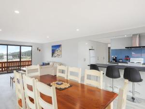 
a kitchen with a table, chairs and a refrigerator at Forsters Bay Haven in Narooma
