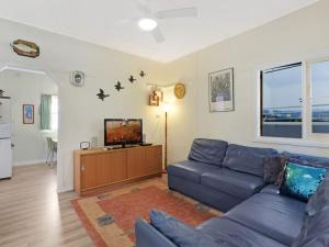 a living room with a blue couch and a tv at Pet Friendly Beach Cottage @ Ballingalla in Narooma