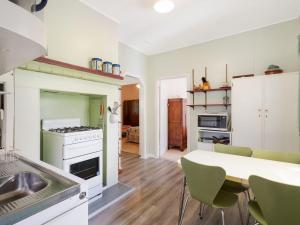 a kitchen with a sink and a table with chairs at Pet Friendly Beach Cottage @ Ballingalla in Narooma