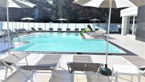 una gran piscina con sillas y sombrilla en Hotel Helvetia en Lignano Sabbiadoro