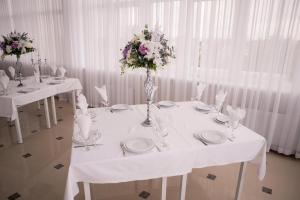 einen weißen Tisch mit Platten und Blumen darauf in der Unterkunft Отель-ресторан “Le Grand” in Schytomyr